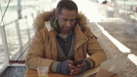Mann-Schreibt-SMS-Per-Smartphone-Im-Straßencafé
